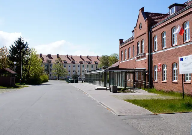 Droga wewnętrzna przed ceglanym budynkiem z wiatą przystankową na terenie Morskiego Ośrodka Szkoleniowego