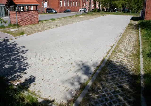 Plac utwardzony kostką ażurową i betonową przy ceglanym budynku Morskiego Ośrodka Szkoleniowego w Kołobrzegu