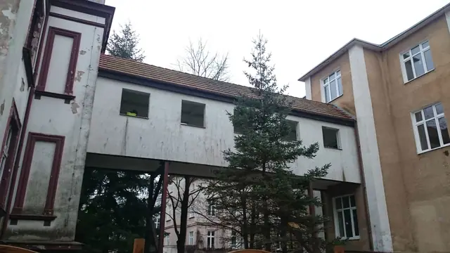 Boczna elewacja opuszczonego budynku z widocznym łącznikiem do sąsiedniej kamienicy