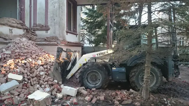 Ładowarka teleskopowa Terex zbiera gruz i cegły spod rozbieranej elewacji willi