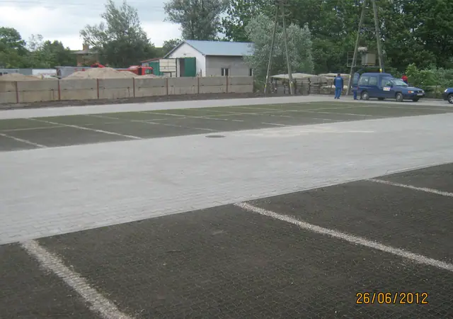 Ukończony parking z zieloną kratą trawnikową i liniami wyznaczającymi miejsca postojowe