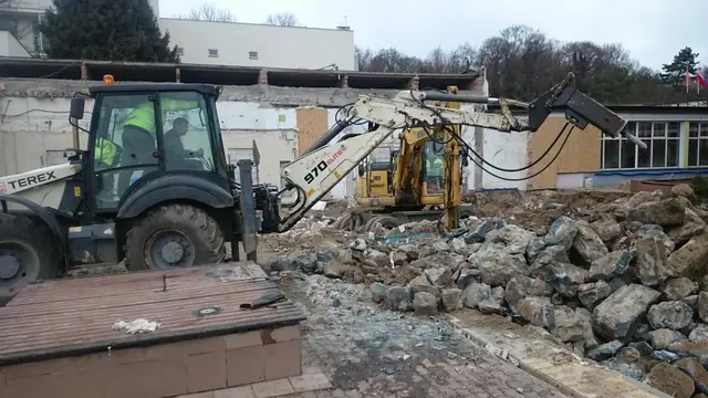 Koparko-ładowarka z młotem hydraulicznym kruszy gruz betonowy na terenie Centrum Verano w Kołobrzegu