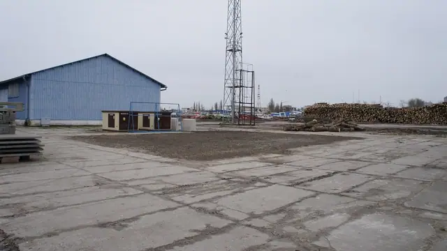 Betonowy plac Portu Handlowego z niebieskim budynkiem i wieżą kratownicową
