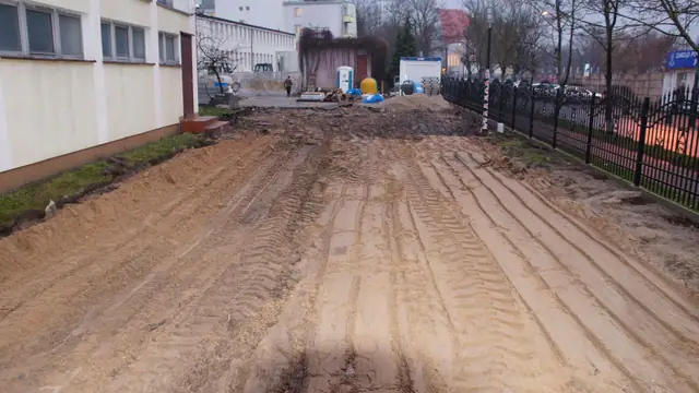 Świeżo wyrównany pas ziemi ze śladami kół wzdłuż ogrodzenia terenu sanatorium