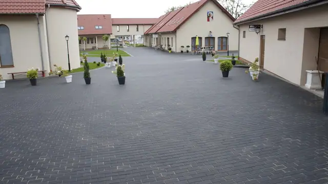 Różowa barokowa fasada kościoła z prowadzącą do niej aleją z ciemnej kostki brukowej