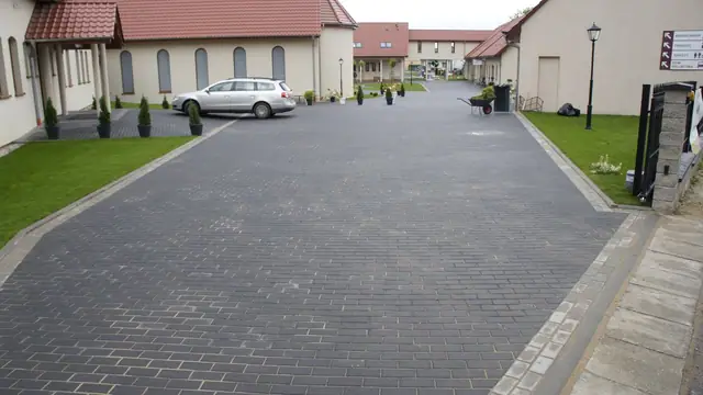 Wykończony dziedziniec z kostki brukowej z widokiem na wieżę kościelną i drzewa