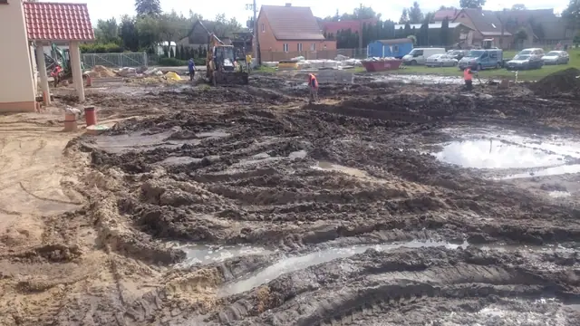 Rozjeżdżony błotnisty plac budowy przy Sanktuarium w Skrzatuszu z głębokimi koleinami po sprzęcie
