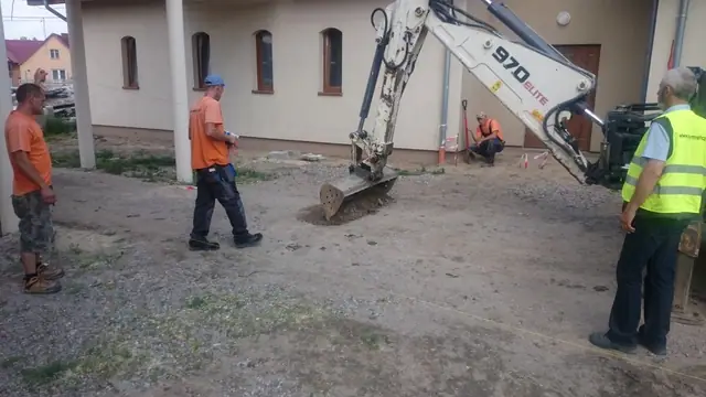 Robotnik idzie po świeżo ułożonej ciemnej kostce brukowej na rozległym placu