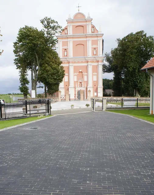 Wybrukowana ścieżka wzdłuż zielonych trawników obok budynku Domu Pielgrzyma