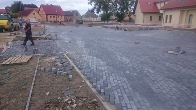 Wykończony dziedziniec z kostki brukowej pomiędzy budynkami, zaparkowany samochód i latarnia
