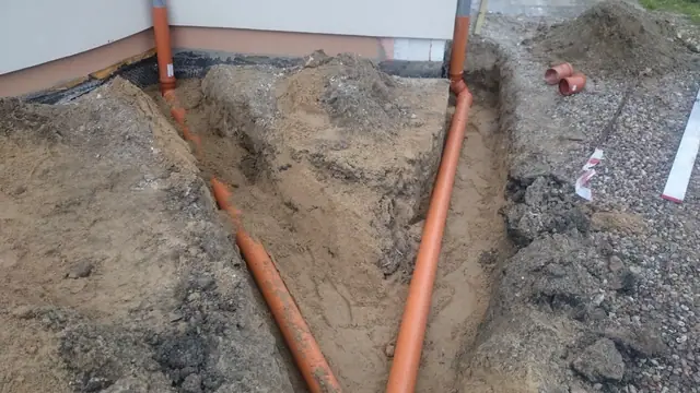 Zbliżenie na trójnik rur kanalizacji deszczowej osadzony w kamienistym wykopie
