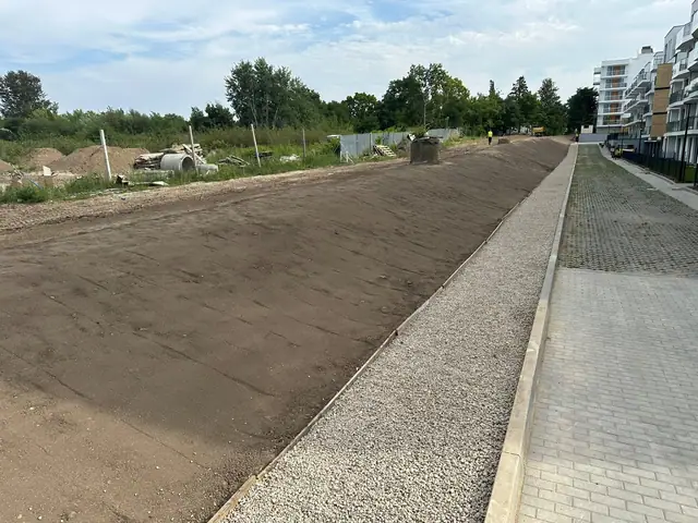 Skarpa pokryta świeżą warstwą ziemi obok chodnika z kostki brukowej w Ustroniu Morskim