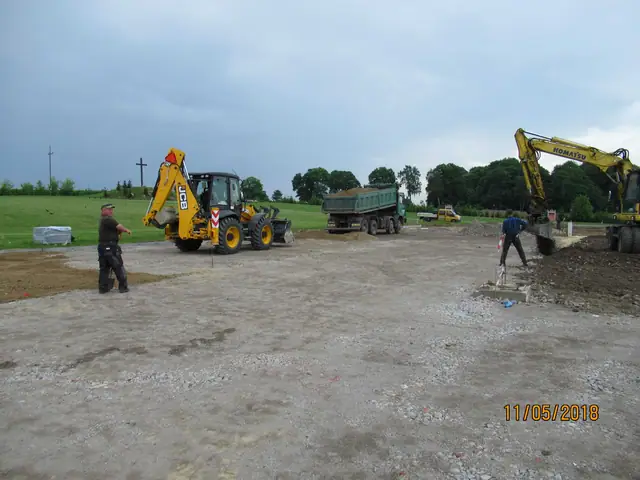 Koparko-ładowarka i wywrotka dowożą kruszywo na warstwę podbudowy pod przyszły plac