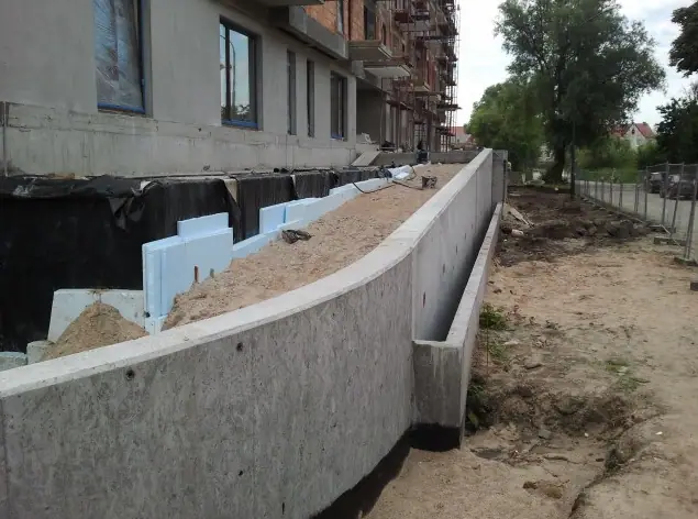 Łukowy betonowy mur oporowy z izolacją termiczną ze styropianu wzdłuż fundamentu budynku