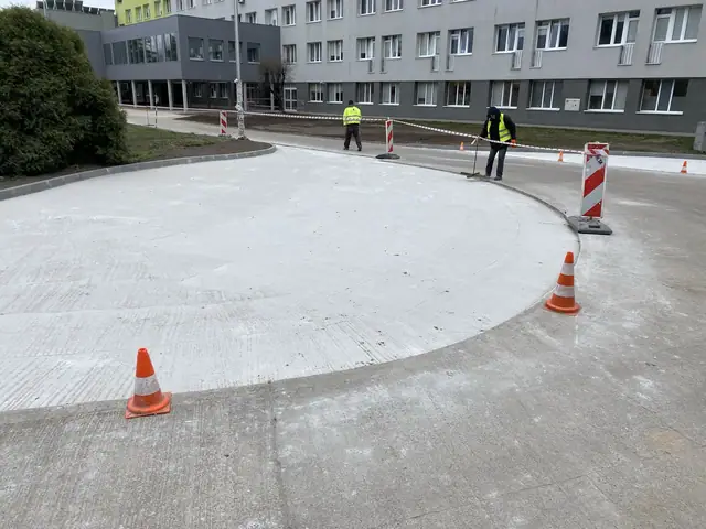 Druga strona zakrzywionej nawierzchni betonowej z pachołkami ostrzegawczymi