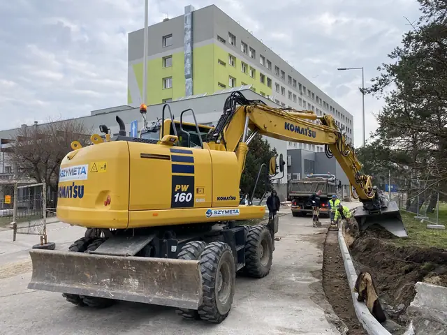 Koparka kołowa Komatsu pracuje przy nowym krawężniku w pobliżu budynku szpitala