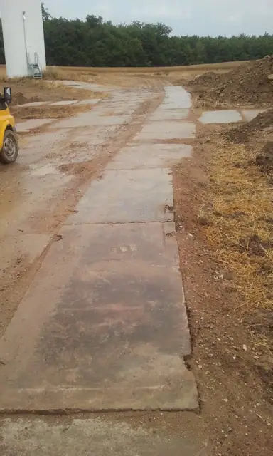 Droga technologiczna z betonowych płyt prowadząca przez pole na farmie wiatrowej w Tymieniu