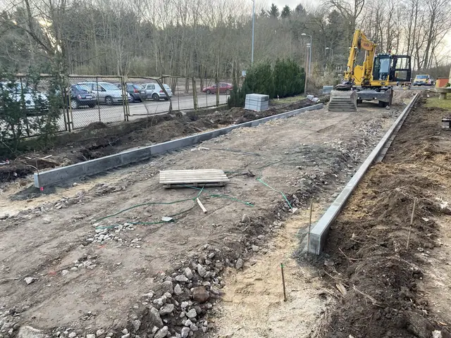 Betonowy krawężnik nowej drogi obok koparki na placu z ułożoną kostką