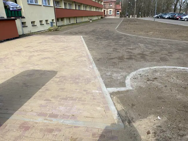 Zakończony fragment placu z czerwono-beżowej kostki brukowej z łukowym wjazdem