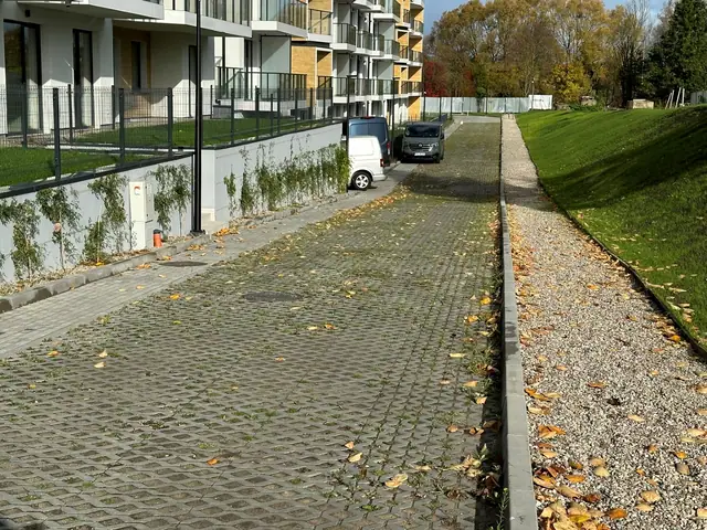 Chodnik z kostki brukowej prowadzący wzdłuż obsypanej żwirem skarpy przy ogrodzeniu