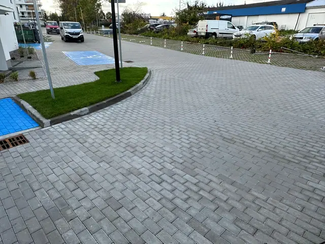Niebieskie miejsca postojowe dla niepełnosprawnych na parkingu z kostki brukowej osiedla