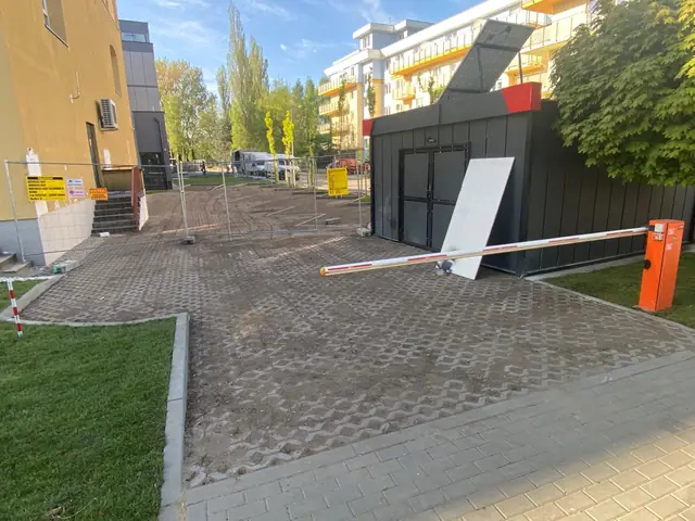 Plac manewrowy z kostki brukowej z szlabanem i kontenerem biurowym budowy