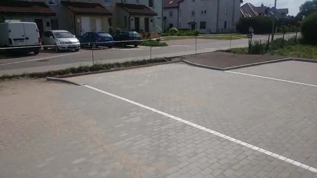 Gotowy parking z szarej kostki brukowej z białymi liniami wyznaczającymi miejsca postojowe