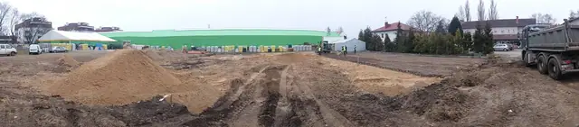 Pryzma kruszywa na piaszczystym placu budowy przy zielonej hali centrum