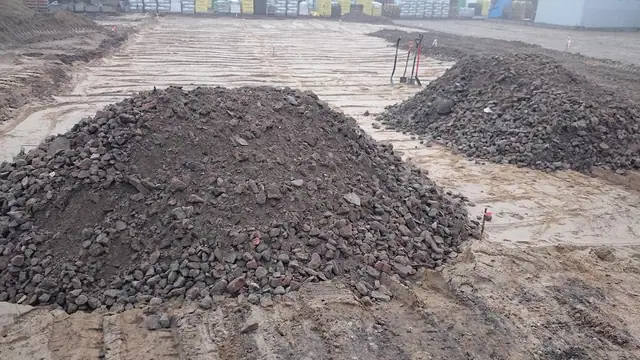 Dwie pryzmy kruszywa na wyrównanym terenie przygotowanym pod kostkę